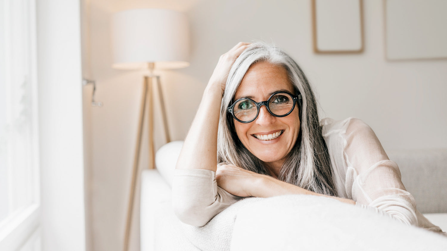 woman sitting on a white coach smiling 